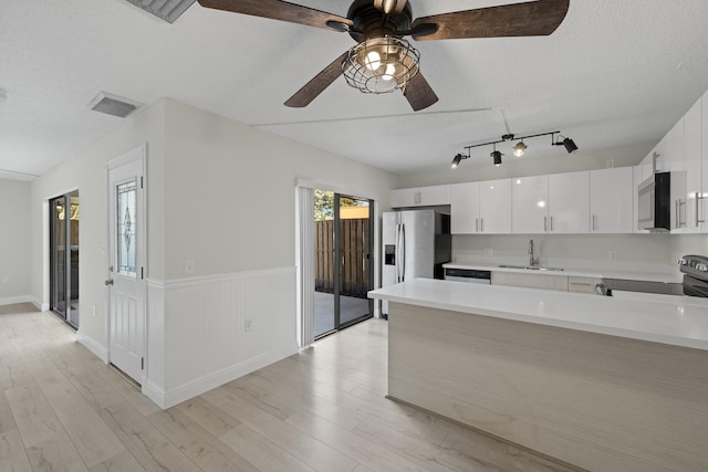 kitchen featuring sink, light hardwood / wood-style flooring, a textured ceiling, appliances with stainless steel finishes, and white cabinetry