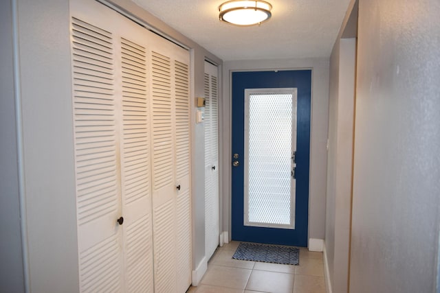 doorway to outside with light tile patterned floors and a textured ceiling