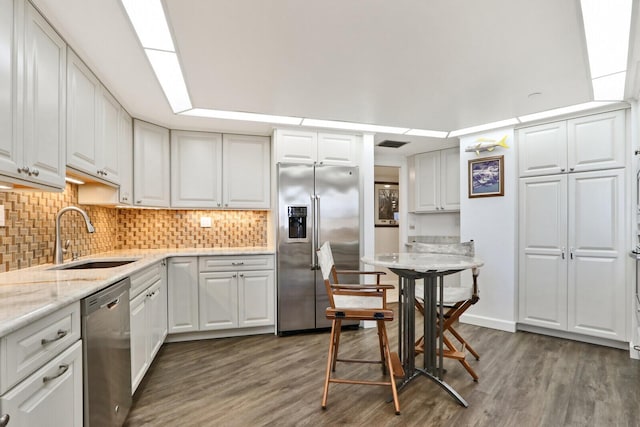 kitchen featuring appliances with stainless steel finishes, tasteful backsplash, dark wood-type flooring, sink, and white cabinetry