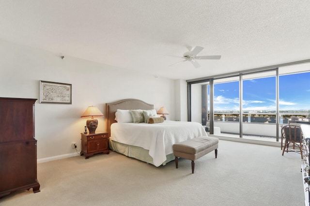 carpeted bedroom with access to outside, ceiling fan, a textured ceiling, and a wall of windows