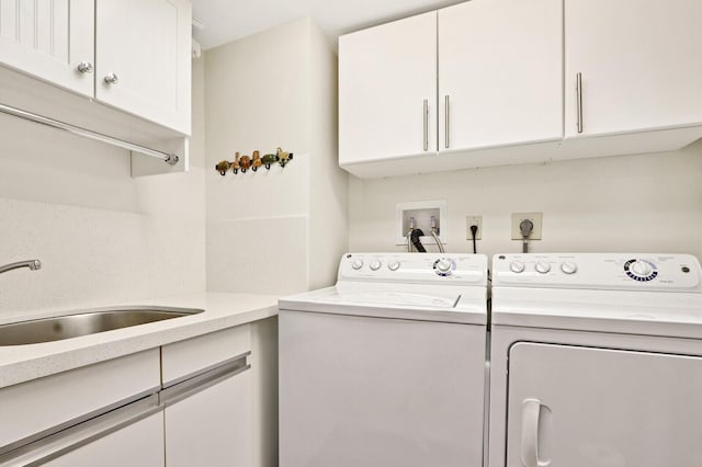 washroom with cabinets, sink, and washing machine and clothes dryer