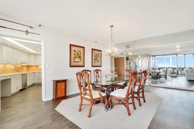 dining room with a textured ceiling, sink, a chandelier, and dark hardwood / wood-style floors