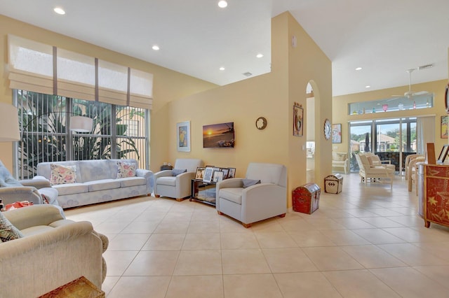 tiled living room with ceiling fan and a towering ceiling