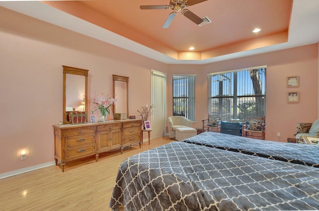 bedroom featuring light hardwood / wood-style floors, a raised ceiling, and ceiling fan