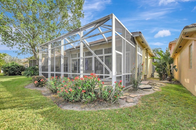 rear view of property with glass enclosure and a yard