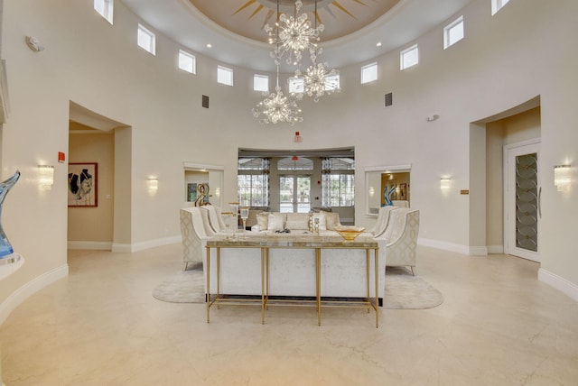 living room featuring a notable chandelier, a raised ceiling, a high ceiling, and french doors