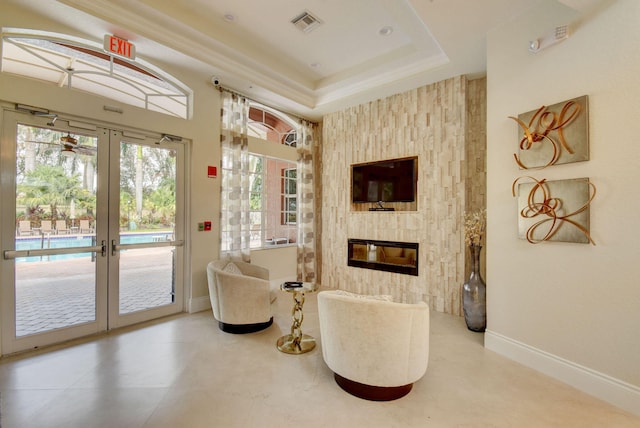 living area with plenty of natural light, a large fireplace, french doors, and a tray ceiling