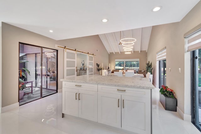 kitchen featuring pendant lighting, lofted ceiling, a barn door, and white cabinetry