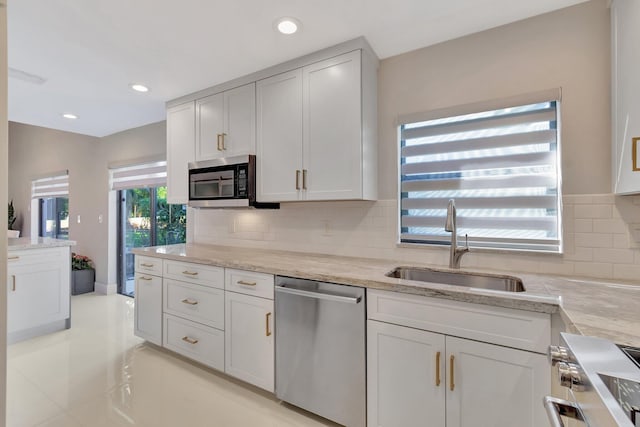 kitchen with white cabinets, backsplash, sink, and stainless steel appliances