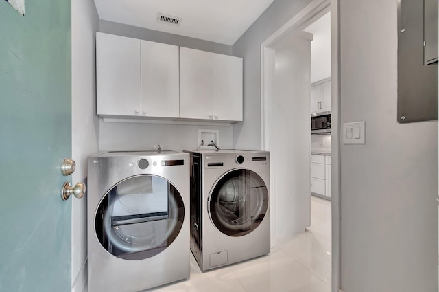 laundry area with cabinets, independent washer and dryer, and light tile patterned floors