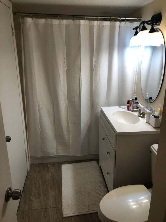 bathroom with vanity, hardwood / wood-style flooring, toilet, and walk in shower