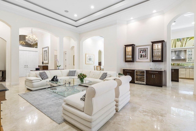 living room featuring a chandelier, a high ceiling, wine cooler, and ornamental molding