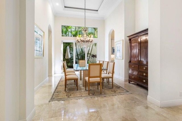 dining area with crown molding, plenty of natural light, a towering ceiling, and a chandelier