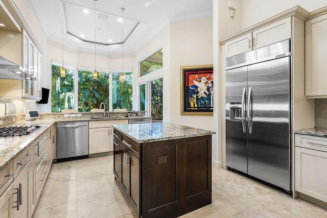 kitchen with light stone counters, stainless steel appliances, tasteful backsplash, and cream cabinets