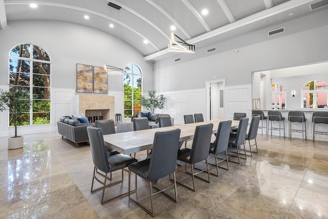 dining space with beam ceiling and high vaulted ceiling