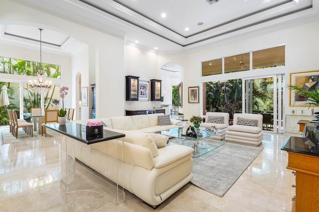 living room with a notable chandelier, a towering ceiling, and a tray ceiling