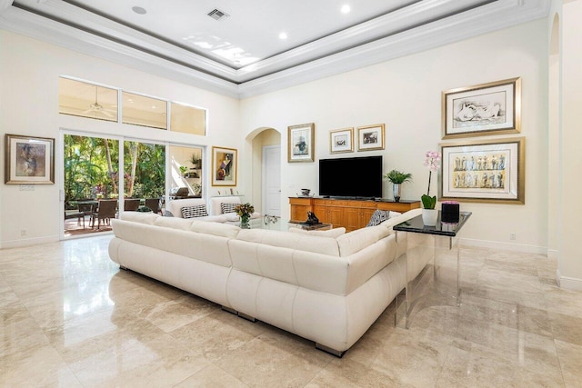 living room with a towering ceiling, a raised ceiling, and crown molding