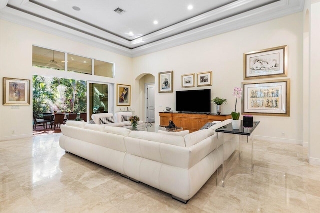 living room with a high ceiling, a tray ceiling, and ornamental molding