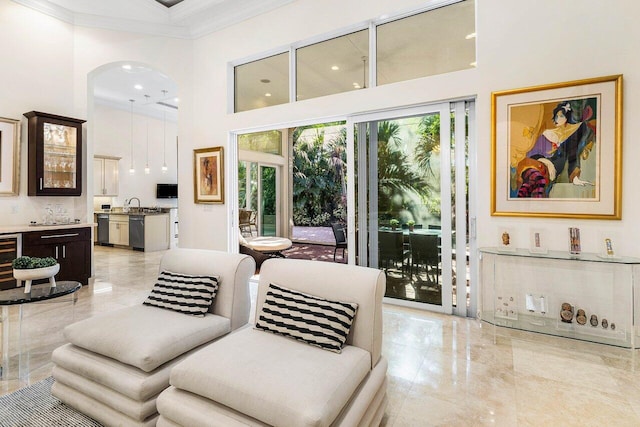 living room featuring beverage cooler, sink, crown molding, and a high ceiling