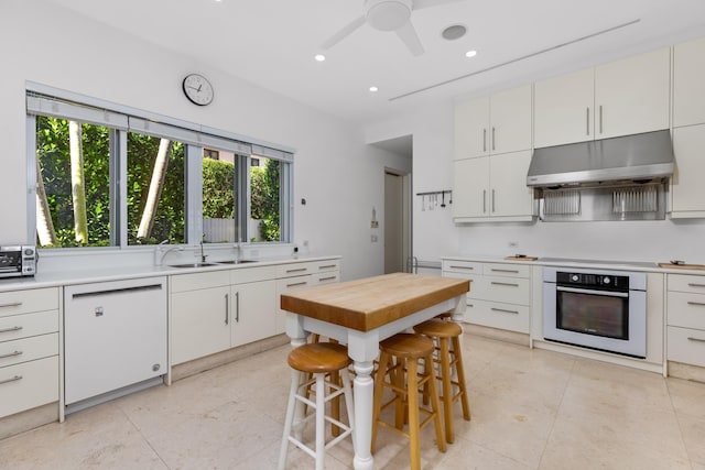 kitchen with a kitchen bar, white cabinetry, dishwasher, and oven