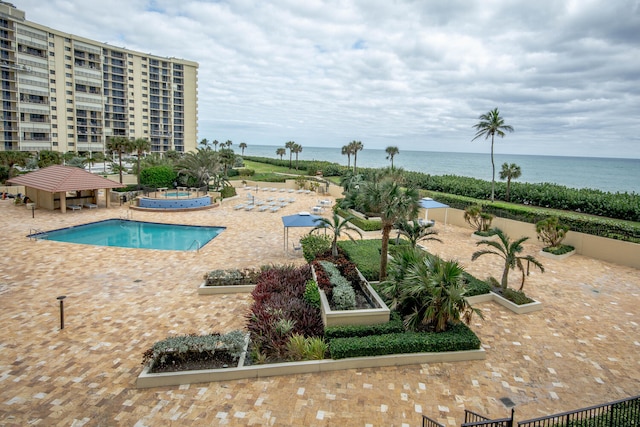 view of pool featuring a water view and a patio