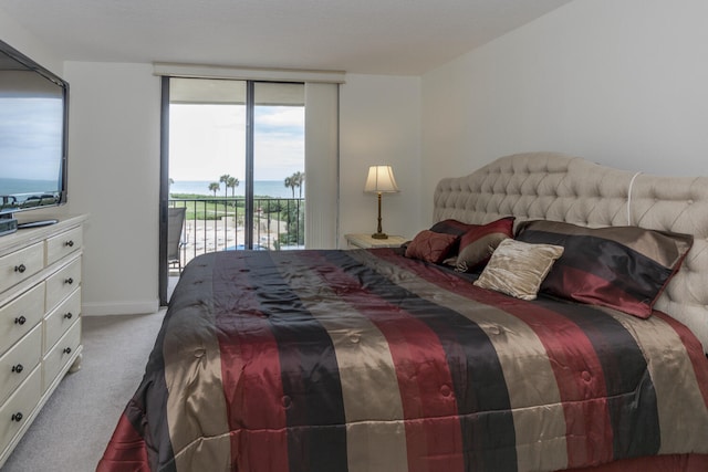 bedroom with access to outside, light colored carpet, and a water view