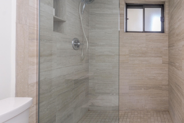 bathroom with toilet and a tile shower