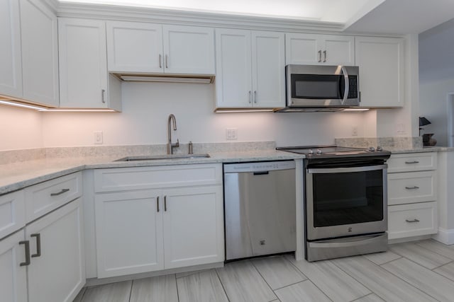 kitchen with light stone countertops, white cabinetry, sink, and stainless steel appliances