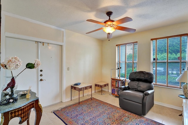 living area featuring ceiling fan, light tile patterned flooring, a healthy amount of sunlight, and a textured ceiling