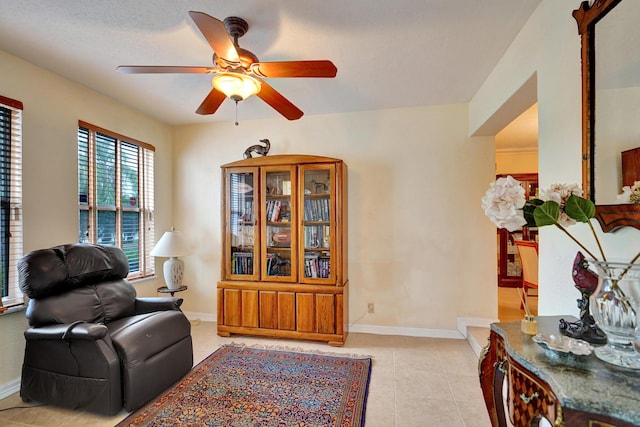 living area featuring ceiling fan, light tile patterned floors, and a textured ceiling