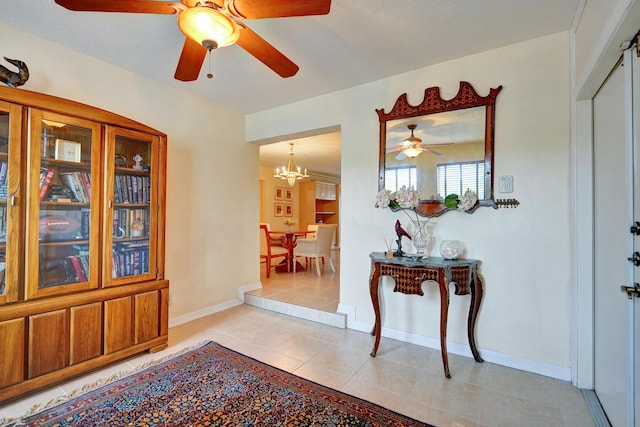 tiled foyer entrance with ceiling fan with notable chandelier