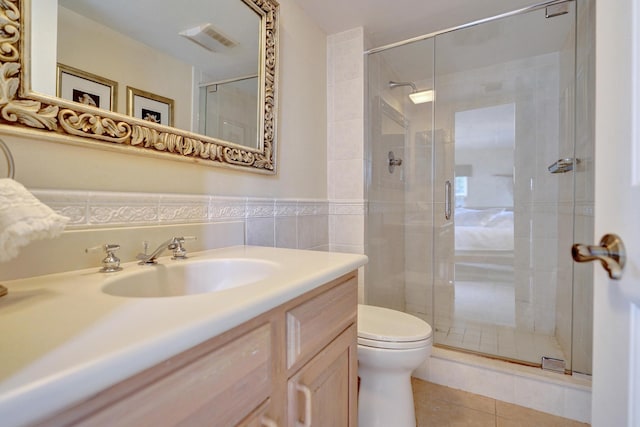 bathroom with tile patterned flooring, a shower with door, tile walls, and toilet