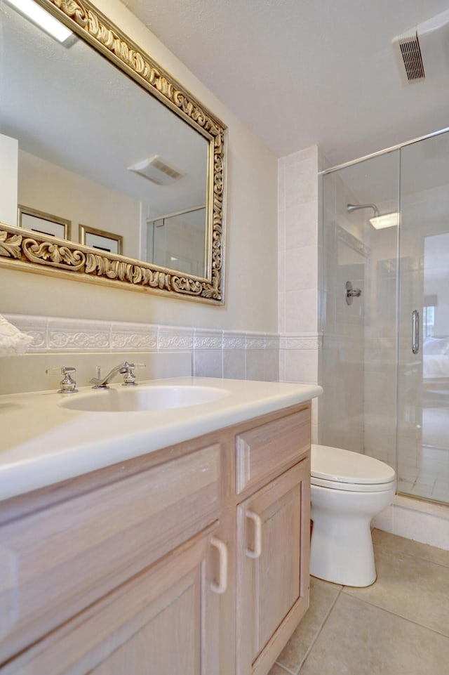 bathroom featuring tile patterned flooring, vanity, toilet, and a shower with door