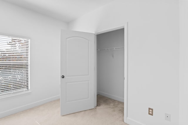 unfurnished bedroom featuring light colored carpet and a closet