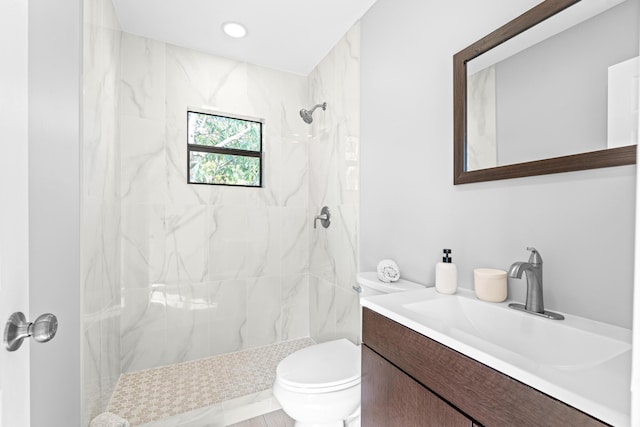 bathroom with vanity, toilet, and a tile shower