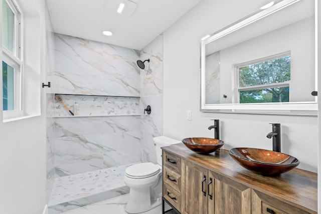 bathroom with a tile shower, vanity, and toilet