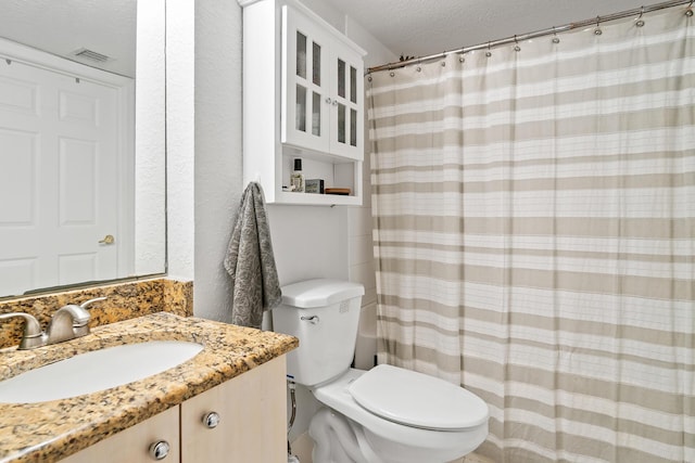 bathroom with vanity, a textured ceiling, and toilet