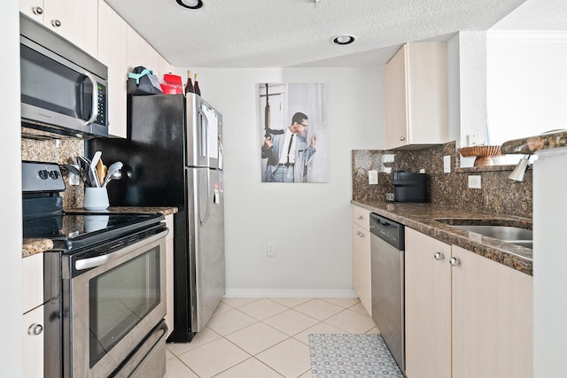 kitchen with white cabinets, appliances with stainless steel finishes, a textured ceiling, and dark stone counters