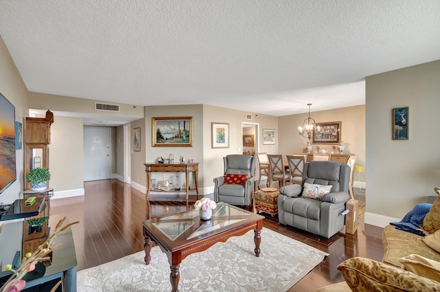 living room featuring a notable chandelier, dark hardwood / wood-style flooring, and a textured ceiling