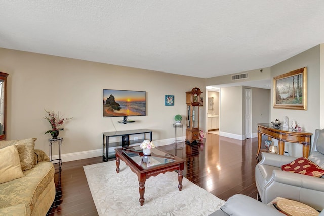 living room featuring dark wood-type flooring and a textured ceiling