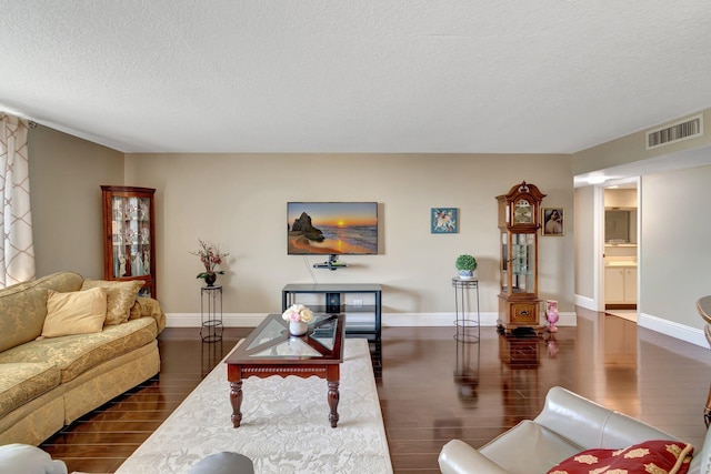 living room with a textured ceiling and dark hardwood / wood-style floors