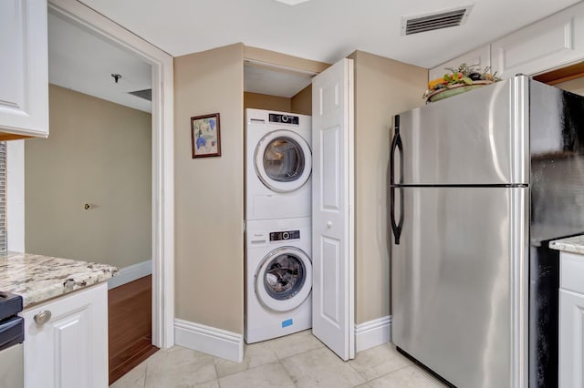 laundry area with light hardwood / wood-style floors and stacked washer / dryer