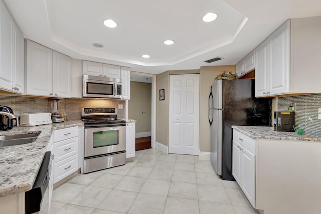 kitchen featuring white cabinets, appliances with stainless steel finishes, a raised ceiling, and sink