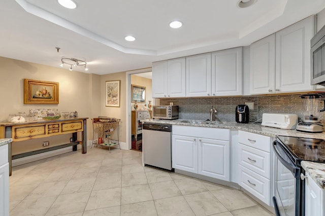 kitchen featuring appliances with stainless steel finishes, a tray ceiling, and white cabinetry