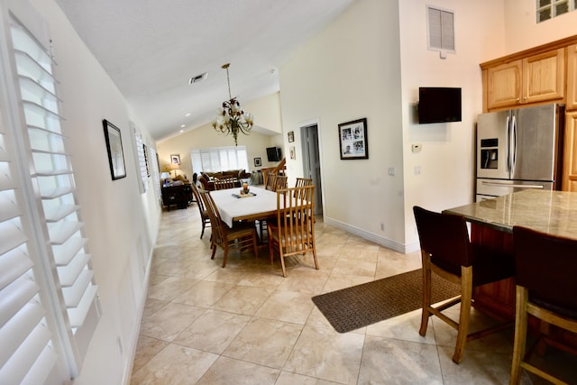 tiled dining room featuring high vaulted ceiling and an inviting chandelier