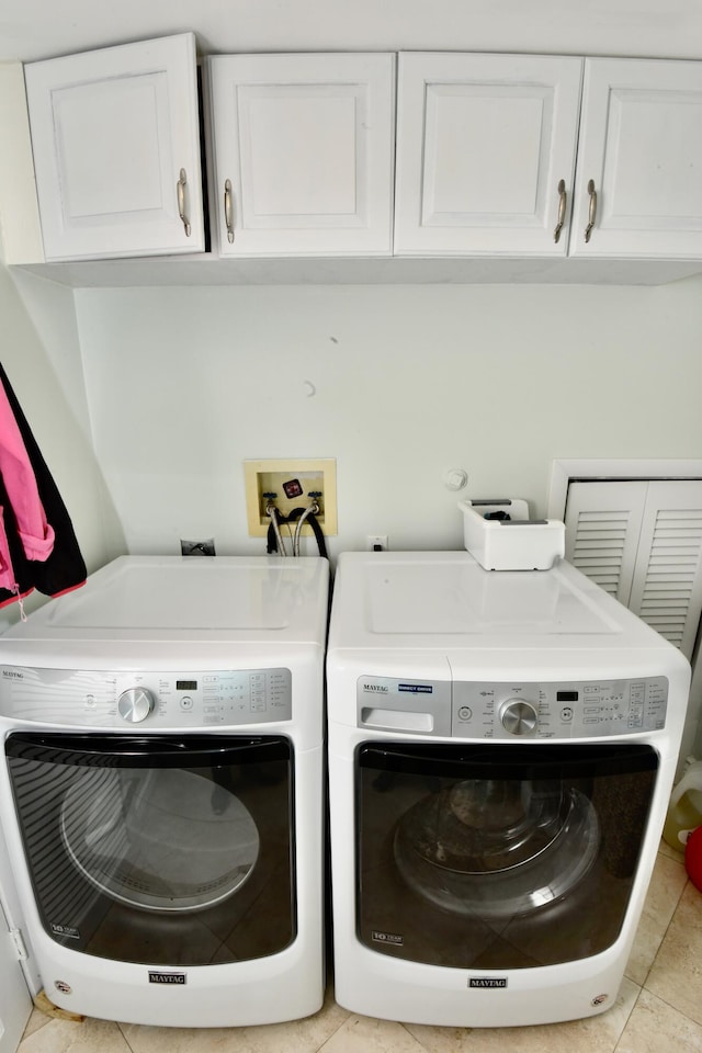 laundry room with cabinets, light tile patterned floors, and washing machine and clothes dryer