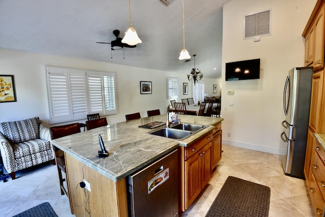 kitchen featuring pendant lighting, sink, light stone countertops, an island with sink, and stainless steel appliances