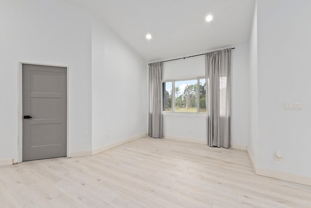 spare room featuring vaulted ceiling and light wood-type flooring