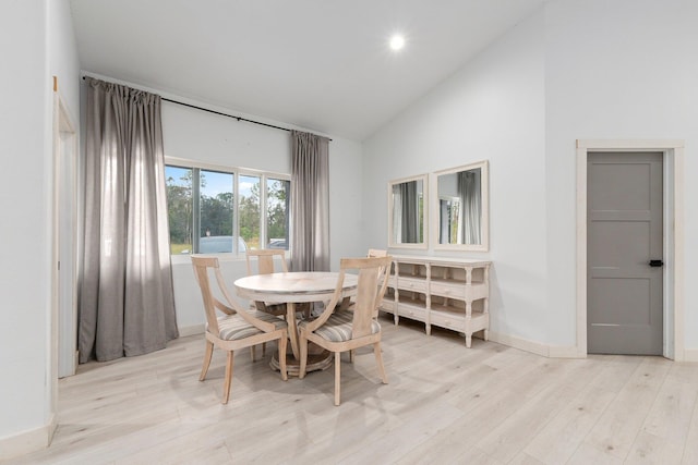 dining area with light wood-type flooring and high vaulted ceiling