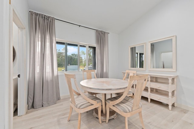 dining space featuring vaulted ceiling and light wood-type flooring